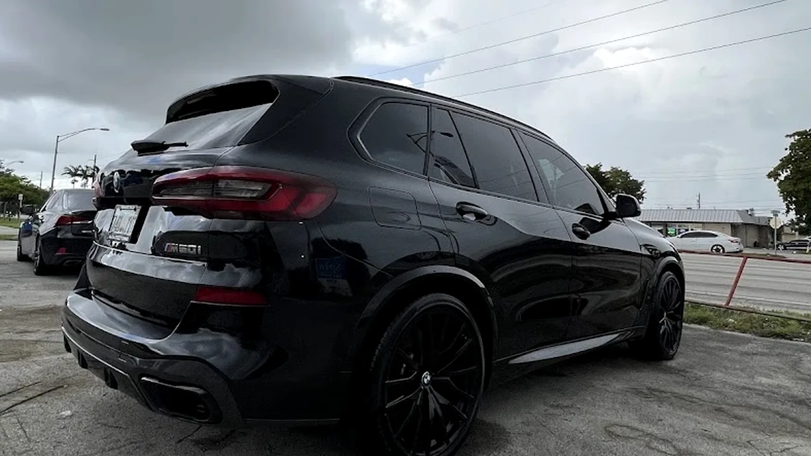 Close-up studio showcase of a ceramic-coated sapphire-black forged wheel and sculpted fender arch with water beading