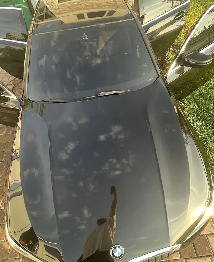 Real mirror sky reflection on a freshly polished black BMW hood with BMW Roundel emblem